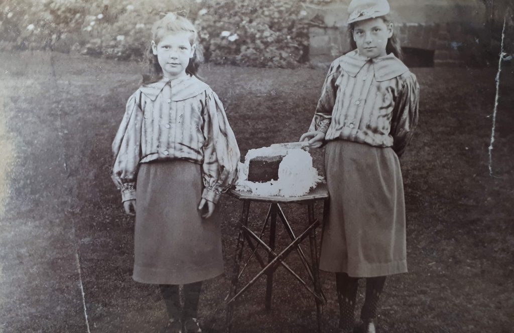 May and Marjorie Bradley protecting sister Jinksie`s 21st birthday cake, Wolverley, Southport 1905